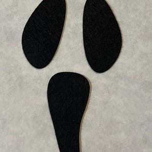 May include: Three black felt pieces shaped like eyes and a mouth, resembling a ghost.