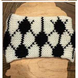 May include: A black and white knitted headband with a checkered pattern.
