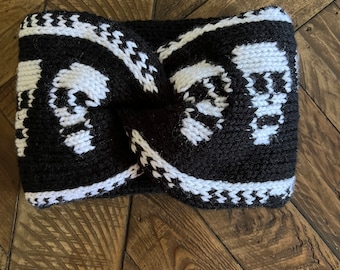 Puede incluir: Diadema de punto negro y blanco con un patrón de calavera. La diadema está doblada por la mitad y tiene un nudo en el medio.