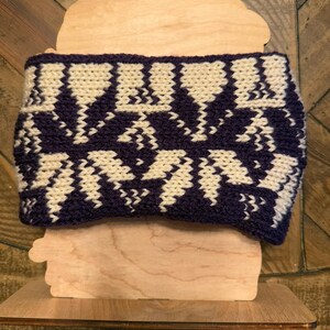 May include: A knitted headband with a geometric pattern in shades of purple and cream.