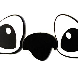 May include: A pair of large, white googly eyes with black pupils and a black beak in the center.