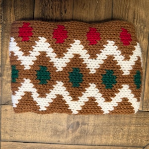 May include: A brown, white, green, and red crocheted headband with a geometric pattern.