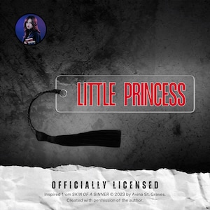 Può includere: Un segnalibro in acrilico trasparente con la scritta "LITTLE PRINCESS" in rosso. Il segnalibro ha un nappa nera attaccata. Una piccola immagine circolare di una donna si trova nell'angolo in alto a sinistra. Lo sfondo è grigio scuro.