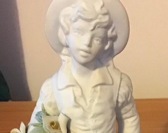 White statuette of a boy holding bouquet of flowers