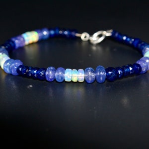 May include: A blue and white gemstone bracelet with a silver clasp. The bracelet is made with blue and white beads.