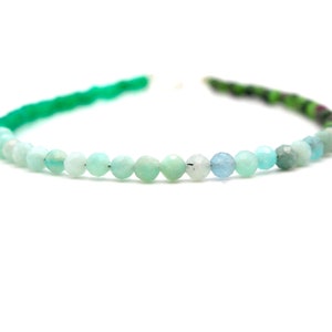 May include: A green, blue, and white gemstone bracelet with round beads. The bracelet is made of natural stones and is a beautiful piece of jewelry.