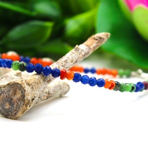Può includere: Un braccialetto multi-color con perline blu, verdi e arancioni. Il braccialetto è realizzato con perline di pietre preziose e ha una chiusura argentata.