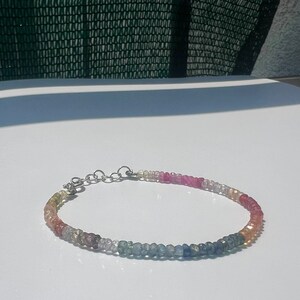 Può includere: Un braccialetto delicato fatto di piccole pietre preziose multicolori. Il braccialetto è fatto di un arcobaleno di colori, tra cui rosa, rosso, giallo, verde, blu e trasparente. Il braccialetto è fatto di una catena d'argento.