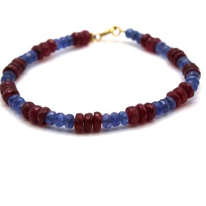 Può includere: Un braccialetto fatto di perline di pietre preziose blu e rosse. Le perline sono sfaccettate e hanno una finitura lucida.