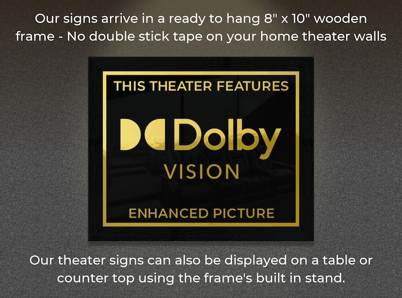 May include: A black framed sign with gold lettering that reads "This Theater Features Dolby Vision Enhanced Picture". The sign is 8 inches by 10 inches and is ready to hang on a wall.