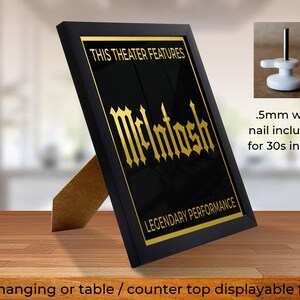 May include: Black framed print with gold text that reads "This Theater Features McIntosh Legendary Performance". The frame has a stand for tabletop display and a nail for wall hanging.