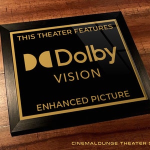 May include: Black framed sign with gold lettering that reads "This theater features Dolby Vision Enhanced Picture".