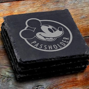 May include: A set of black slate coasters with a gray Mickey Mouse silhouette and the text "Passholder" in a circle around him.