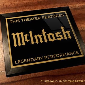 May include: Black framed sign with gold lettering that reads "This Theater Features McIntosh Legendary Performance".