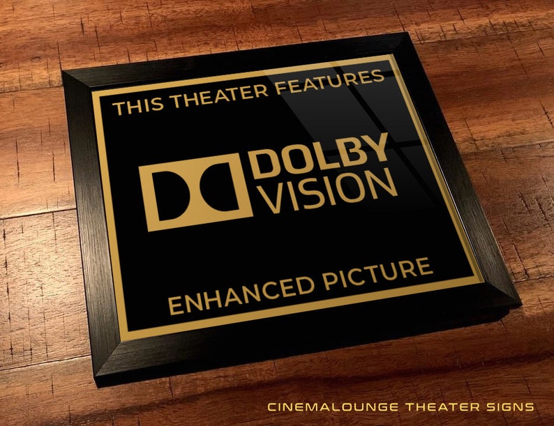 May include: Black framed sign with gold lettering that reads "This theater features Dolby Vision Enhanced Picture". The Dolby Vision logo is a gold "D" inside a square.