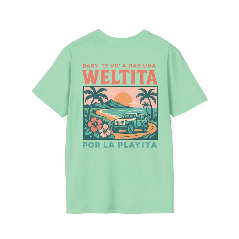 May include: A light green t-shirt featuring a beach scene with a blue jeep, palm trees, and flowers. The text on the shirt reads "BABY, TE VO' A DAR UNA WELTITA POR LA PLAYITA" in orange and green.