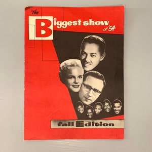 May include: A red and black magazine cover with the text "The Biggest Show of '54 Fall Edition". The cover features a group of people, including a woman with blonde hair and a man with glasses.