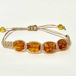 Pode incluir: Um bracelete de macram&eacute; castanho com quatro contas de &acirc;mbar.