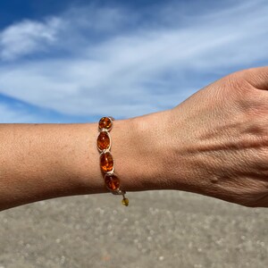 Pode incluir: Um bracelete com contas ovais marrons e um cord&atilde;o bege. O bracelete est&aacute; no pulso de uma pessoa.