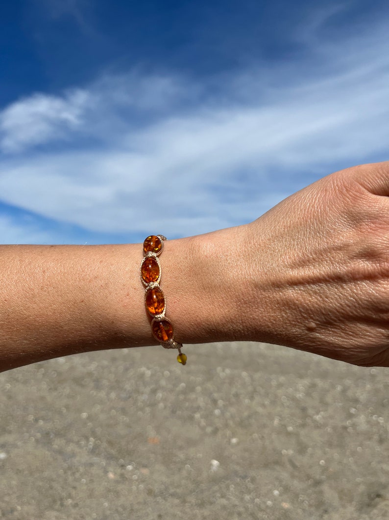 Pode incluir: Um bracelete com contas ovais marrons e um cord&atilde;o bege. O bracelete est&aacute; no pulso de uma pessoa.