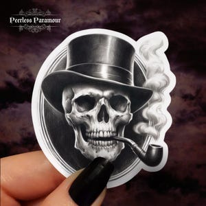 May include: A black and white sticker of a skull wearing a top hat and smoking a pipe. The skull is in a circular frame with a smoke plume coming from the pipe.