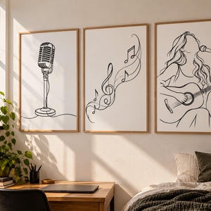 Pode incluir: Um conjunto de três quadros de parede com desenhos de linhas pretas sobre fundo branco. O quadro da esquerda mostra um microfone vintage, o central exibe notas musicais e uma clave de sol, e o da direita retrata uma pessoa a cantar.