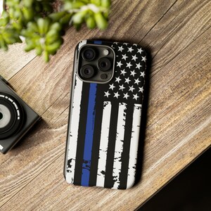 May include: A black phone case with a distressed American flag design and a thin blue line running vertically down the center.