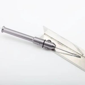 May include: A silver-colored, metal tool with a cylindrical body and a pointed tip. The tool has a handle on one end and a small, black ring near the tip. It is placed on a clear, angled surface.