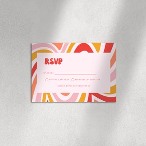 May include: A pink RSVP card with a colorful abstract design. The card has a section for the guest's name and two options: Joyfully Accepts and Regretfully Declines. The card also includes the text "Kindly Reply by February 15."