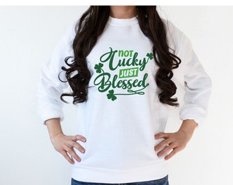 May include: White sweatshirt with green shamrock designs and the text "Not Lucky Just Blessed".