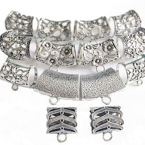 Op de afbeelding: Een set zilverkleurige metalen sieradenbevestigingen met ingewikkelde bloemmotieven. De bevestigingen zijn in de vorm van buizen en vierkanten en hebben kleine lussen om aan sieraden te bevestigen.