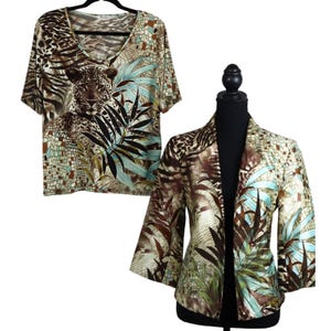 May include: A short-sleeved V-neck top and a three-quarter sleeve jacket. Both garments feature a jungle-themed print with a leopard, palm leaves, and a mix of brown, teal, and beige tones. The jacket is displayed on a black mannequin.