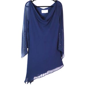 May include: A navy blue dress with a cowl neckline and asymmetrical hemline. The long sleeves are sheer with sequin embellishments near the cuffs. The dress is hanging on a black hanger.