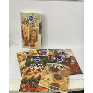 May include: A collection of Pillsbury holiday cookbooks. The main book features a gingerbread house illustration and the text "HOLIDAY COOKING COLLECTION." Other books include "FESTIVE HOLIDAY FAVORITES" and "HOME FOR THE HOLIDAYS."