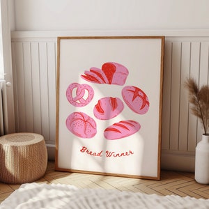 Op de afbeelding: Een witte poster met een rode en roze illustratie van verschillende soorten brood. De tekst "Bread Winner" staat in het rood onderaan de poster.
