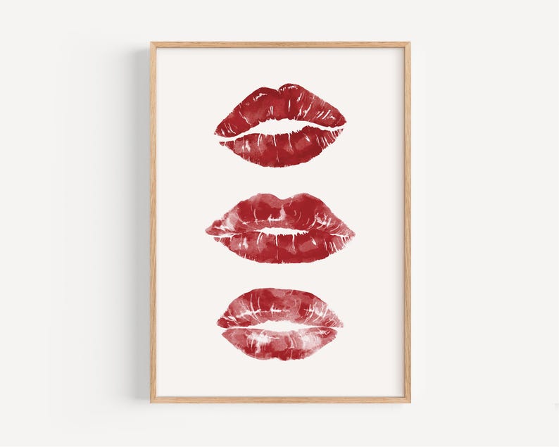 Puede incluir: Tres huellas de l&aacute;piz labial rojo en una fila sobre un fondo blanco, enmarcadas en un marco de madera claro.