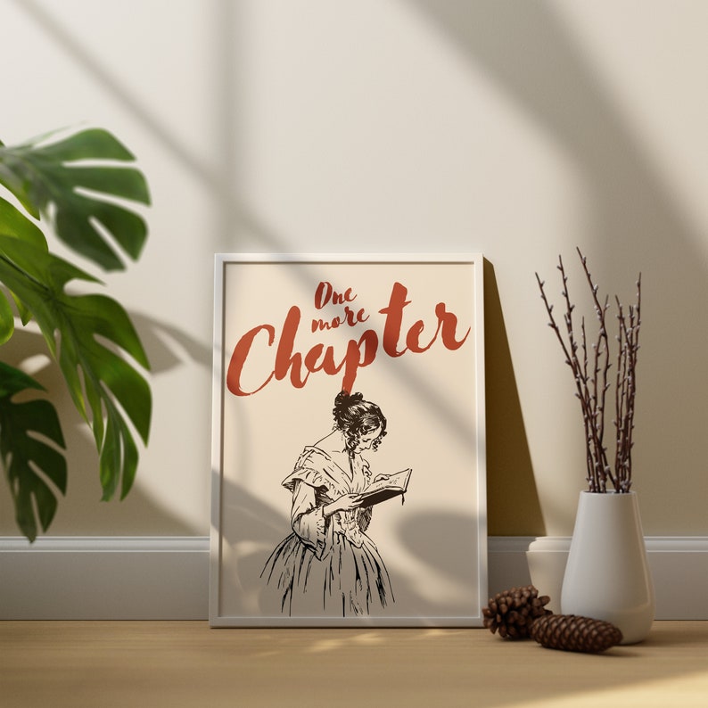 May include: A white framed print with a black and white illustration of a woman reading a book. The text "One more Chapter" is written in red above the illustration.