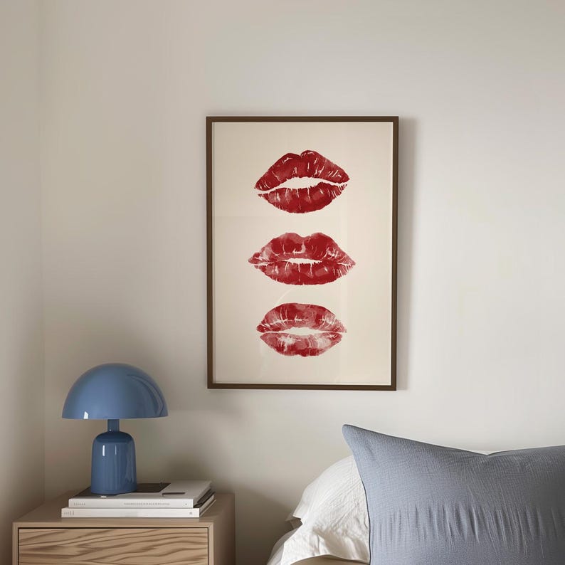 Puede incluir: Una impresi&oacute;n enmarcada con tres marcas de besos de l&aacute;piz labial rojo en una fila vertical sobre un fondo blanco.