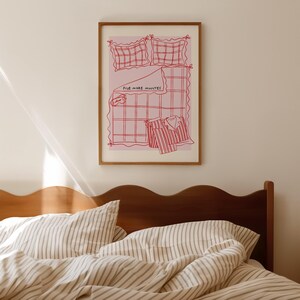 Puede incluir: Una ilustraci&oacute;n enmarcada de una cama con fondo rosa. La cama est&aacute; hecha con un patr&oacute;n de cuadros rojos y blancos y tiene una camisa a rayas rojas y blancas en la parte superior. El texto "Five More Minutes" est&aacute; escrito en rojo en la cama.