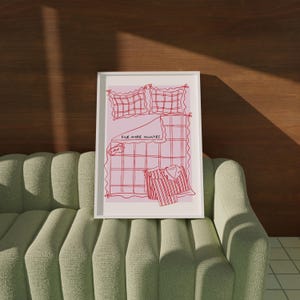 Puede incluir: Una impresi&oacute;n enmarcada en blanco con un fondo rosa y dibujos de l&iacute;neas rojas de una cama con un patr&oacute;n a cuadros, almohadas y una camisa. El texto "Five more minutes" est&aacute; escrito en la cama.