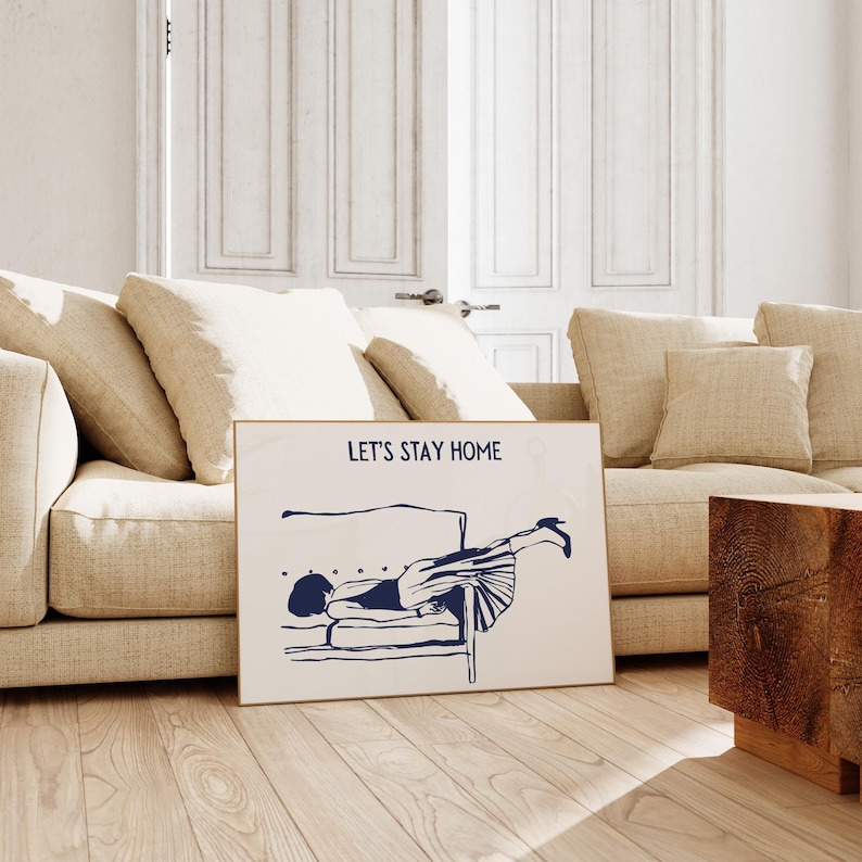 May include: A white poster with blue text and a blue illustration of a person lying upside down on a couch. The text on the poster reads "Let's Stay Home".