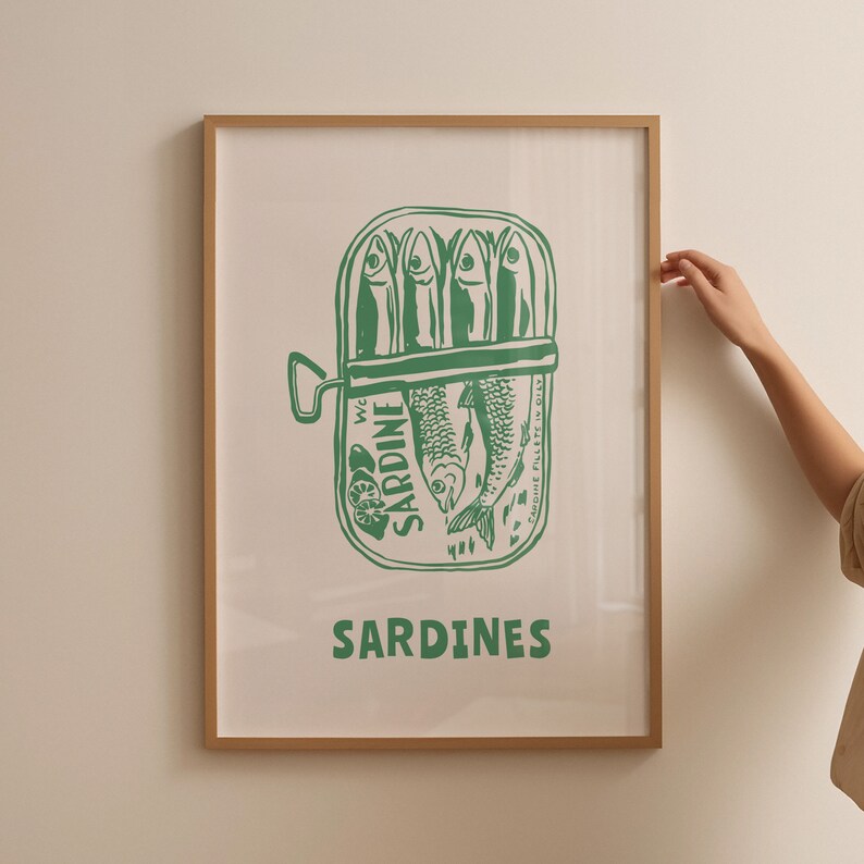 May include: A green and white illustration of a can of sardines with the text "We Sardine" and "Sardines" on a white background in a wooden frame.