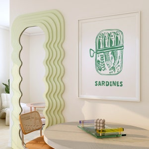 May include: A white framed print with a green illustration of a can of sardines. The can has the word "SARDINE" printed on it and the text "SARDINES" is printed below the can.