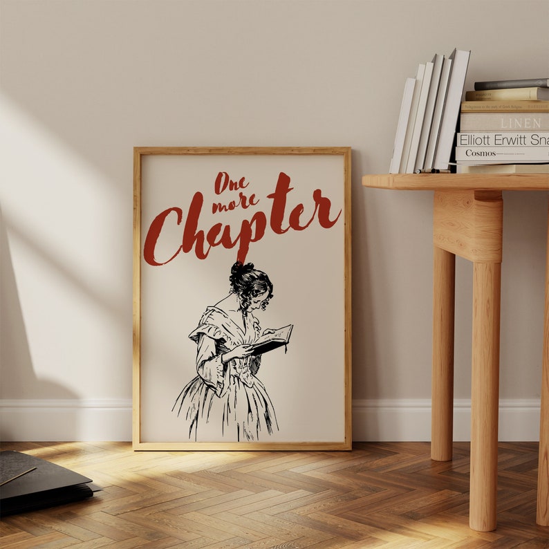May include: A framed print with a black and white illustration of a woman reading a book. The text "One more Chapter" is written in red cursive above the illustration.