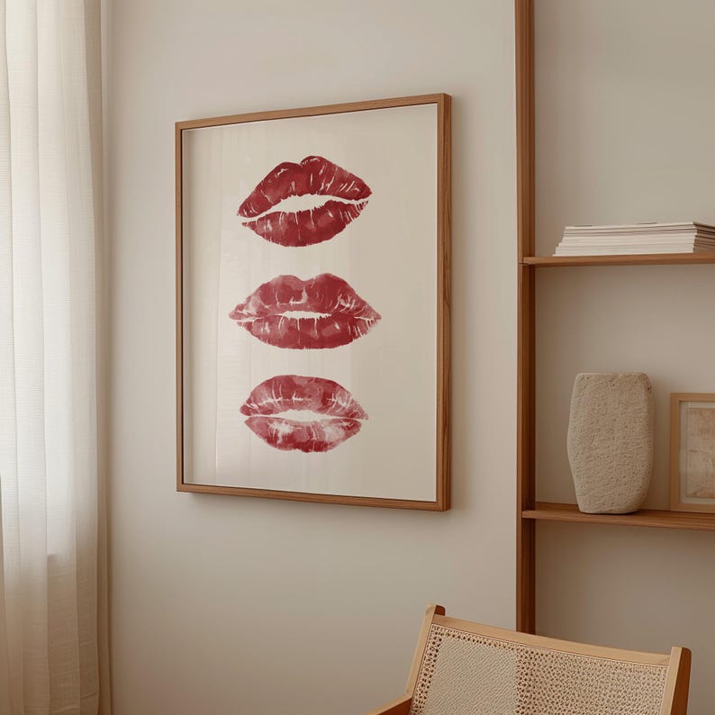 Puede incluir: Una impresi&oacute;n enmarcada con tres marcas de besos de l&aacute;piz labial rojo sobre un fondo blanco. El marco es de madera y tiene un acabado marr&oacute;n claro.