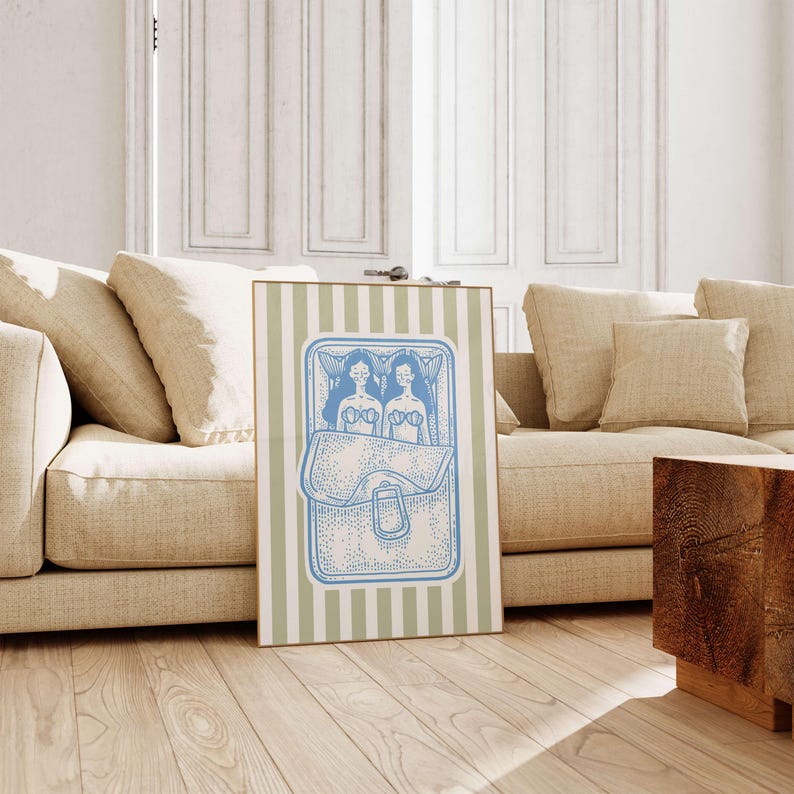 Pu&ograve; includere: Una stampa artistica incorniciata con un'illustrazione blu e bianca di due figure in un letto, all'interno di una cornice a forma di borsa. La stampa ha uno sfondo a righe in verde chiaro e bianco. L'opera d'arte &egrave; esposta in un soggiorno.