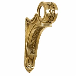 Peut inclure: Un support d'étagère en laiton poli présentant une silhouette incurvée avec une ouverture circulaire sur le dessus. Le design comprend des sculptures complexes en forme de feuilles autour de l'anneau supérieur et une incrustation texturée en losange.