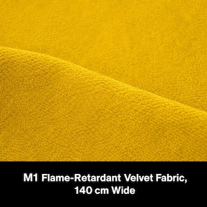 May include: A mustard yellow velvet fabric with a textured surface. The text at the bottom of the image reads: M1 Flame-Retardant Velvet Fabric, 140 cm Wide. The fabric is folded to show the depth and consistent color of the material.