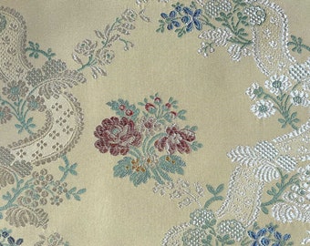 Può includere: Un tessuto beige con un motivo floreale ripetitivo. I fiori sono in tonalità di rosa, rosso, blu e verde. Il tessuto ha una leggera lucentezza.