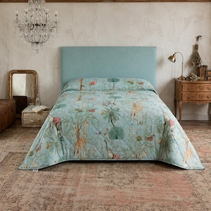 Peut inclure: Un couvre-lit matelassé bleu clair orné d'un motif répétitif de girafes, d'éléphants, de flamants roses et de palmiers. La literie recouvre un lit doté d'une tête de lit bleu clair assortie, présentant un imprimé détaillé sur le thème de la jungle.